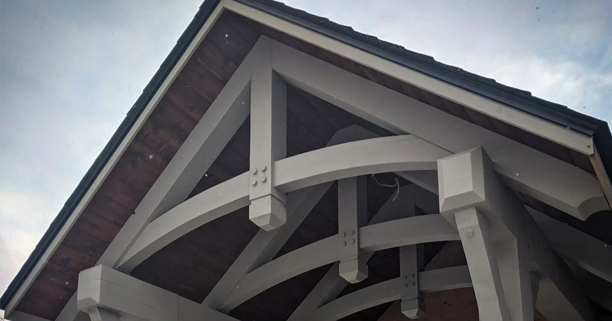 Curved painted timber truss detail under roofline.